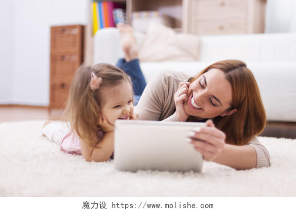 可爱的小女孩和妈妈在家里使用数字平板电脑